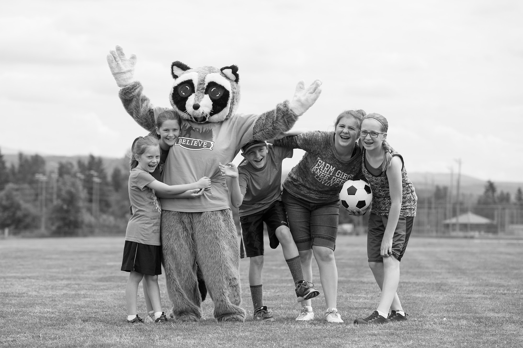 raccoon mascot posing with kid soccer players