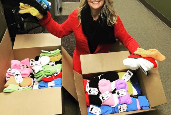 woman kneeled down in front of boxes of fuzzy socks holding some up