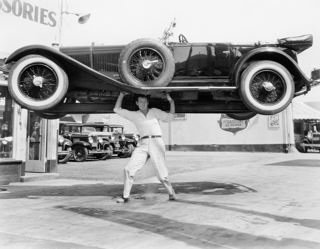 old photo of a man lifting a car over his head