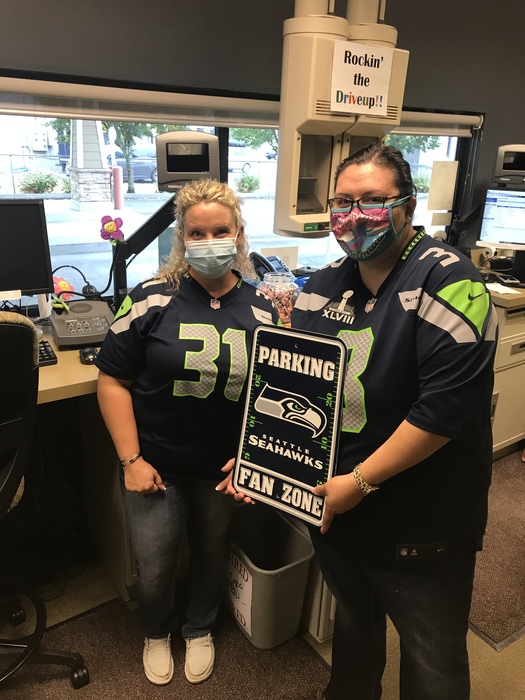 2 people wearing Seahawks jerseys holding sign
