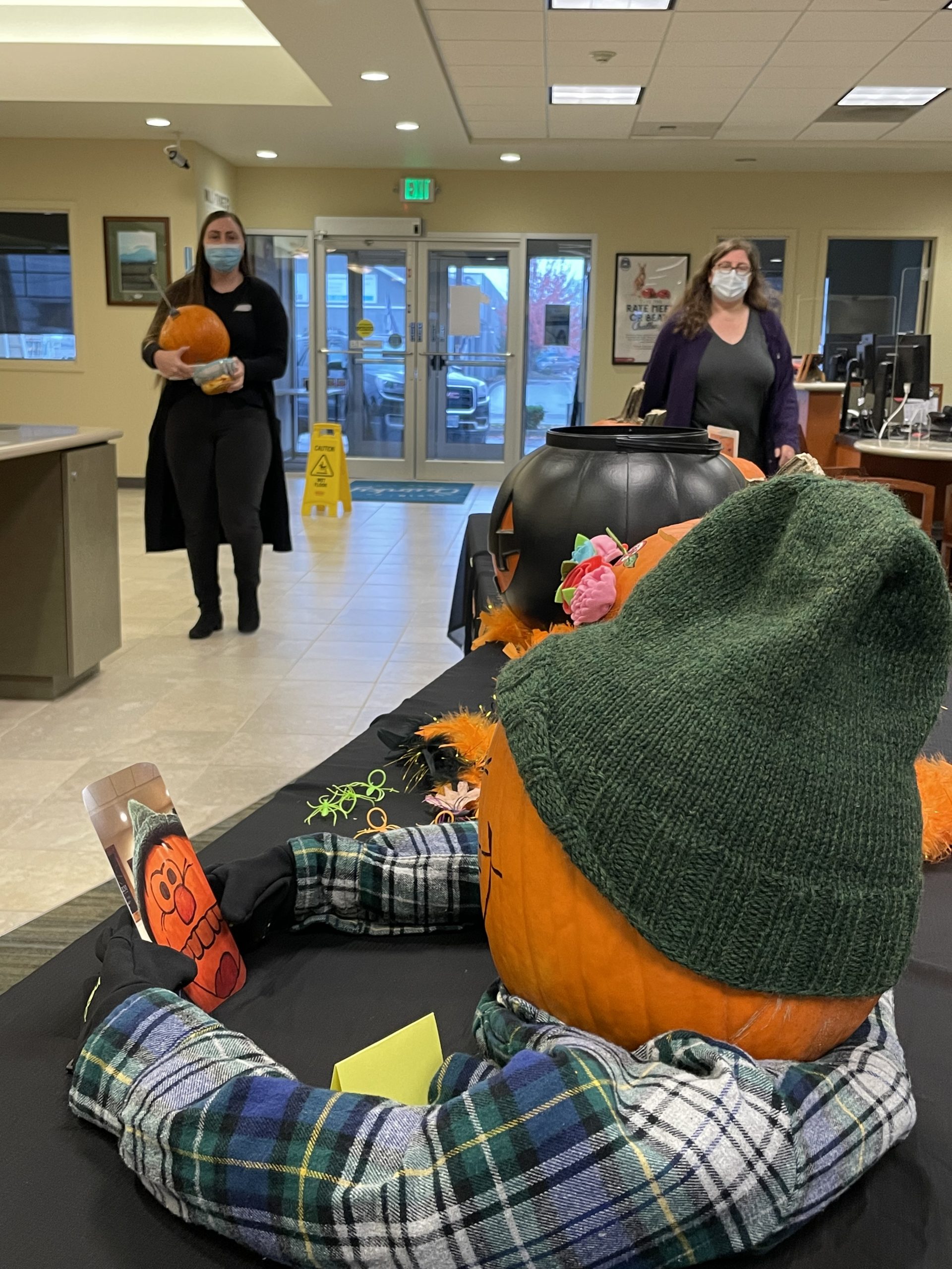 pumpkin decorated with hat anf flannel shirt holding phone