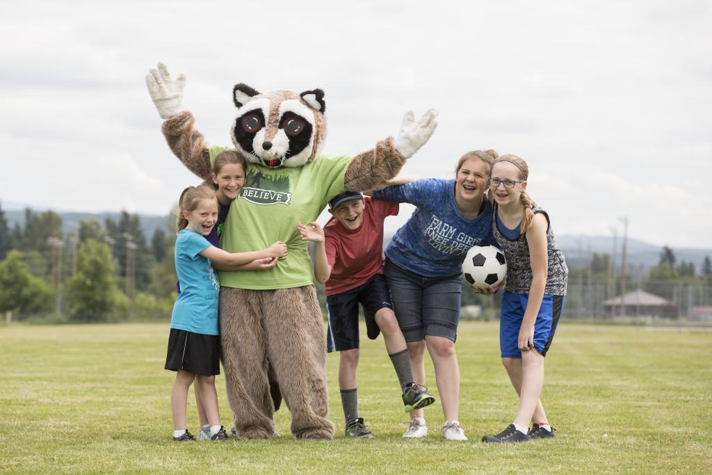 Rocky Raccoon mascot with kids on soccer field