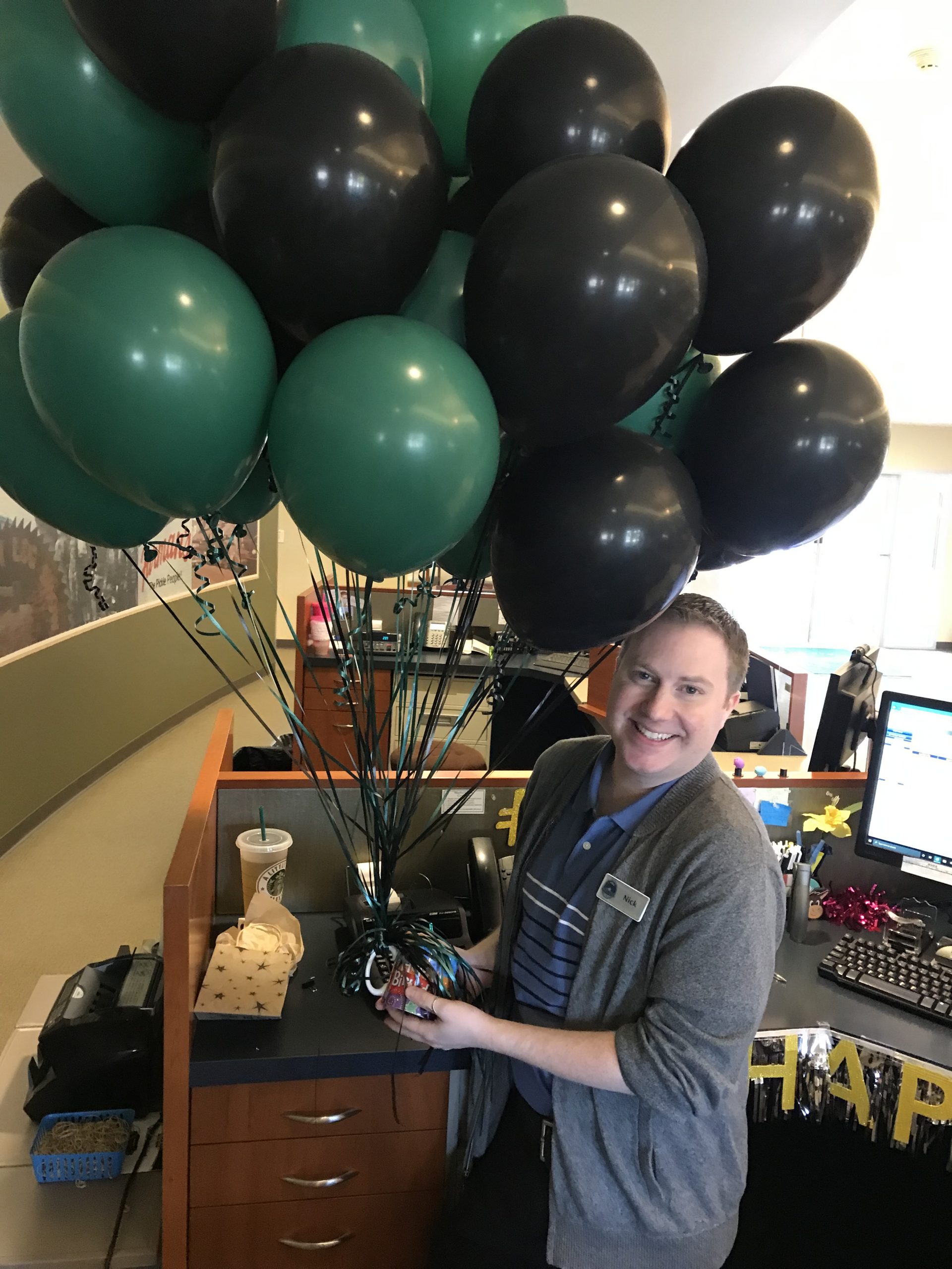 man holding bunch of green and black balloons