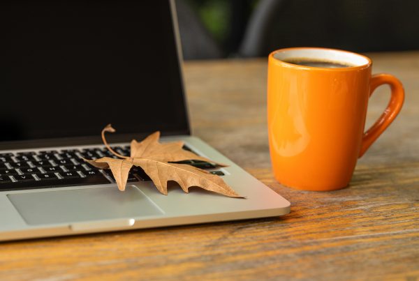 A computer showing free financial webinars with a fall leaf and a coffee cup.