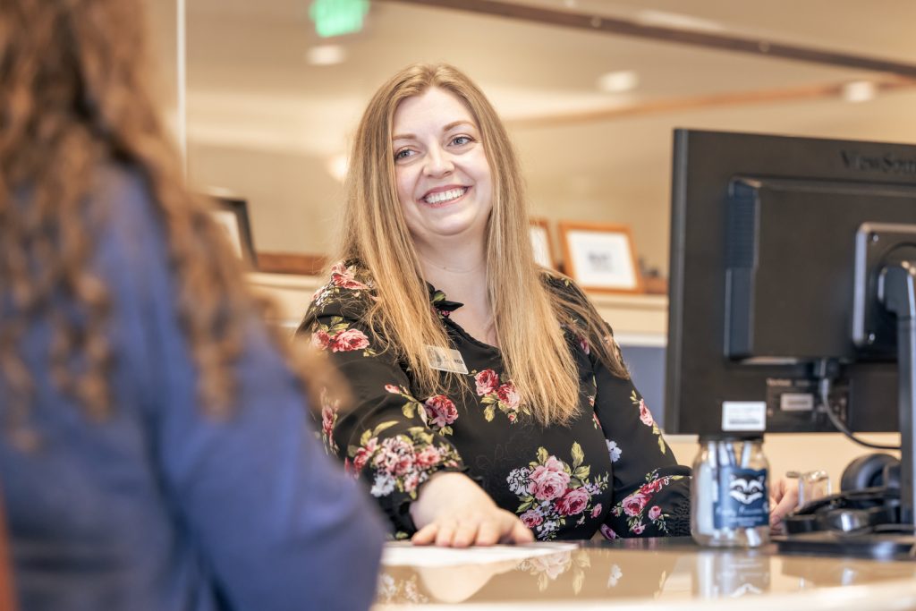 A credit union worker smiling at the person she is helping learn how to use a personal loan